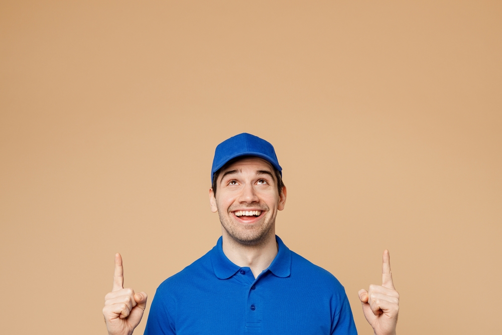 A plumber in a blue shirt pointing up for preventative maintenance